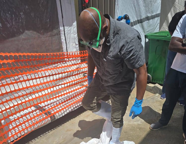 Team member donning protective overshoes at the controlled entry point to the isolation area